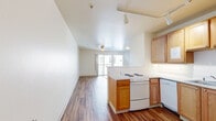 Located at 1700 Pierce St in Lakewood, Colorado, this 2-bedroom, 1-bathroom unit offers a practical and comfortable single-floor layout with consistent hardwood-style flooring carried throughout every room, lending a cohesive, warm aesthetic to the entire space.

The open living area is bright and welcoming, anchored by a ceiling fan and large sliding glass doors that lead to a private balcony, allowing generous natural light and outdoor views. A wall-mounted HVAC unit provides climate control directly in the living space.

The kitchen is efficiently designed in an L-shaped configuration, featuring warm oak cabinetry with ample upper and lower storage, white appliances including a range, dishwasher, and refrigerator, and a peninsula with a breakfast bar that separates the kitchen from the living area. Track lighting illuminates the workspace effectively.

Both bedrooms are well-proportioned, each equipped with a ceiling fan and windows that bring in natural light. The primary bedroom includes a spacious sliding-door closet and a baseboard heating unit. The second bedroom also features a large window with exterior views.

The bathroom is clean and functional, offering an accessible walk-in shower with grab bars, a wood-cabinet vanity, and a wall mirror. The consistent flooring continues into the bathroom, maintaining the unit's unified design throughout.