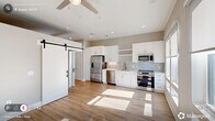 Located at 229 E Chatham St in downtown Cary, NC, this one-bedroom, one-bathroom unit is thoughtfully designed to maximize functionality within a compact footprint. The single-floor layout offers a logical flow connecting the combined kitchen and living area, hallway, bedroom, bathroom, laundry, and utility spaces.

The open kitchen and living room serves as the heart of the unit, featuring light-toned hardwood flooring and natural light streaming through windows. A striking black-hardware sliding barn door adds a modern farmhouse touch and serves as a stylish divider between spaces.

The hallway is bright and well-lit with recessed ceiling lights, flanked by louvered closet doors and clean white trim, reinforcing the unit's crisp aesthetic. The bedroom is carpeted for comfort and features vaulted ceiling height, a ceiling fan, and a built-in sliding-door closet. Neutral wall tones throughout create a calm, cohesive atmosphere.

The bathroom is well-appointed with wood-look flooring, a white vanity with undermount sink, and a fully tiled walk-in shower with a glass enclosure and both fixed and handheld showerheads. Dedicated laundry and utility areas add practical convenience. Clean lines, neutral finishes, and quality materials define this move-in-ready Cary address.