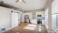 Located at 229 E Chatham St in downtown Cary, NC, this one-bedroom, one-bathroom unit is thoughtfully designed to maximize functionality within a compact footprint. The single-floor layout offers a logical flow connecting the combined kitchen and living area, hallway, bedroom, bathroom, laundry, and utility spaces.

The open kitchen and living room serves as the heart of the unit, featuring light-toned hardwood flooring and natural light streaming through windows. A striking black-hardware sliding barn door adds a modern farmhouse touch and serves as a stylish divider between spaces.

The hallway is bright and well-lit with recessed ceiling lights, flanked by louvered closet doors and clean white trim, reinforcing the unit's crisp aesthetic. The bedroom is carpeted for comfort and features vaulted ceiling height, a ceiling fan, and a built-in sliding-door closet. Neutral wall tones throughout create a calm, cohesive atmosphere.

The bathroom is well-appointed with wood-look flooring, a white vanity with undermount sink, and a fully tiled walk-in shower with a glass enclosure and both fixed and handheld showerheads. Dedicated laundry and utility areas add practical convenience. Clean lines, neutral finishes, and quality materials define this move-in-ready Cary address.