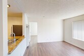 Located at 1059 Casitas Pass Rd in Carpinteria, California, this single-floor unit offers a practical and well-organized layout across its compact footprint. Rich wood-style flooring runs consistently throughout every room, providing a warm, cohesive aesthetic that ties the space together.

The open kitchen and living area serves as the functional heart of the unit. The kitchen features white cabinetry, granite-style countertops, a gas range, stainless steel appliances including a refrigerator and microwave, and a sink with a pass-through counter that connects to the living area. Track lighting overhead keeps the space well-illuminated.

The living room is bright and airy, with crisp white walls, a textured ceiling, and a ceiling fan with a light fixture for added comfort and airflow. A large window fitted with vertical blinds invites natural light and provides a view of the surrounding greenery, enhancing the room's open feel.

A separate room offers additional versatile living space, also finished with the same wood-style flooring and neutral walls beneath a textured ceiling.

The bathroom is clean and functional, featuring a full tub and shower combination with chrome fixtures, a toilet, and matching wood-style flooring that carries through from the rest of the unit. The space is straightforward and well-maintained throughout.