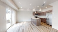 Located at 1586 West Switchgrass Lane in Coeur d'Alene, Idaho, this two-story home offers a clean, contemporary design with thoughtful finishes throughout. The main level showcases an open-concept layout where the kitchen flows seamlessly into the living area. The kitchen is a standout feature, equipped with rich dark-toned cabinetry, stainless steel appliances including a refrigerator with ice maker, microwave, and range, complemented by a large center island with a light countertop, undermount sink, and stylish pendant lighting. Light-toned hardwood flooring runs throughout the main living areas, enhancing the bright and airy atmosphere created by recessed lighting and sliding glass door access. The upper level includes multiple bedrooms carpeted in neutral tones, each benefiting from natural light through generously sized windows with neighborhood views. The primary bedroom features direct access to an en-suite bathroom with warm wood vanity cabinetry. Bathrooms are outfitted with clean white fixtures, including a dedicated walk-in shower with built-in shelving and a separate tub-shower combination unit. A five-panel interior door and staircase landing add refined architectural detail. The home presents a fresh, move-in-ready aesthetic throughout.