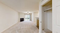 This well-appointed 2-bedroom, 2-bathroom single-floor residence in Harrisburg, Pennsylvania offers a comfortable and functional layout. The open living room serves as the heart of the home, featuring plush wall-to-wall carpeting, a ceiling fan, a classic fireplace, and a sliding glass door that fills the space with natural light and provides direct outdoor access. The adjacent kitchen includes wood-toned cabinetry and connects seamlessly to the living area. Light-toned luxury vinyl plank flooring runs through the kitchen and utility areas, offering a clean contrast to the carpeted living and sleeping spaces. Both bedrooms are generously sized, each outfitted with ceiling fans and large windows that invite natural light. The spacious primary bedroom offers ample room for furnishings. The two bathrooms feature neutral tile flooring, warm wood vanities, and brushed nickel hardware. A dedicated laundry room houses a full-size side-by-side washer and dryer. An additional unclassified room with built-in wooden shelving provides excellent extra storage. The overall aesthetic is clean and neutral, with cream-toned walls and consistent finishes throughout, creating a bright, move-in ready living environment.