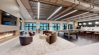 Located at 2551 Frontier Dr in Pittsburgh, PA, this thoughtfully designed single-floor amenity space offers a comprehensive and refined experience across a generous footprint. The open living room serves as the heart of the facility, showcasing an elegant arched window nook with built-in bench seating, globe pendant lighting, and a sleek linear fireplace framed in warm wood paneling — all set against large-format light tile flooring and a coffered wood ceiling that adds architectural depth. Black-framed glass partition doors and barn-style sliding doors connect spaces while maintaining a sense of openness throughout. The kitchen is outfitted with dark stone countertops, a bold marble-look backsplash, stainless steel appliances, and warm globe pendant lighting, combining functionality with upscale design. The dedicated exercise room features commercial-grade Matrix fitness equipment including treadmills, stair climbers, and strength machines, as well as a separate studio space with smart mirror fitness panels and light hardwood flooring flooded with natural light from multiple large windows. A private office nook provides a quiet, focused workspace with stylish finishes. The hallway connects all areas seamlessly, reinforcing the cohesive, contemporary aesthetic that defines this well-appointed community space.
