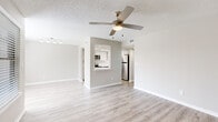 Located at 2639 Granada Bay Drive in Melbourne, Florida, this efficiently designed one-bedroom, one-bathroom residence offers a clean, modern aesthetic throughout. Light wood-style flooring runs continuously across the living spaces, complementing the neutral gray and white color palette that gives the home a fresh, updated feel.

The open-concept living room is airy and well-lit, benefiting from multiple windows that invite natural light and outdoor views. A ceiling fan with integrated lighting adds both comfort and style. The living area flows seamlessly toward the kitchen via a pass-through opening, enhancing the sense of connectivity between spaces.

The kitchen is a standout feature, outfitted with white shaker cabinetry, quartz countertops, a subway tile backsplash, and a full suite of stainless steel appliances including a refrigerator, range, microwave, and dishwasher. Recessed lighting and a window above the sink contribute to a bright and functional workspace.

The bedroom is comfortably sized, featuring a large window for natural light, wood-style flooring, and access to a dedicated closet. The bathroom is clean and simply appointed with a tub-shower combination, white vanity, and coordinating flooring. A hallway connecting the rooms features textured walls and efficient overhead lighting, completing this well-maintained, move-in-ready home.
