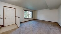 Located at 1860 41st St NW in Rochester, Minnesota, this two-floor home offers a practical and well-organized layout across both levels. The main floor features a spacious living room with plush carpeting, neutral-toned walls, and a large picture window that frames outdoor greenery, filling the space with natural light. Adjacent to the living area, the kitchen is outfitted with warm oak cabinetry, white appliances including a refrigerator, electric range, and dishwasher, complemented by hard surface countertops and hardwood flooring. A sliding glass door provides direct outdoor access, adding both convenience and additional light to the kitchen. The upper level hosts generously sized carpeted bedrooms with ample wall space and windows that allow for natural light. Two bathrooms serve the home, each featuring classic white tile, oak vanities with storage, and clean, functional fixtures. One bathroom includes a full tub and shower combination, while the other offers a compact vanity with a mirrored medicine cabinet. Dark wood interior doors and trim provide a consistent, traditional aesthetic throughout. A staircase connects the two levels, with an open upper landing offering hallway access to the bedrooms and additional closet storage.