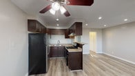 This single-story unit offers a well-organized layout that balances functionality with a clean, updated aesthetic. The open-concept design connects the kitchen and living area, creating a cohesive and practical living space. Light luxury vinyl plank flooring extends throughout, providing a neutral, modern foundation that ties the rooms together.

The kitchen is a standout feature, equipped with rich dark-brown shaker-style cabinetry that reaches toward the ceiling for ample storage. Granite-style countertops provide a durable workspace, complemented by a stainless steel refrigerator, a gas range with a stainless steel hood, and a double-basin sink. A peninsula with bar-height seating creates a natural divide between the kitchen and the open living area, which benefits from recessed lighting and a ceiling fan overhead.

The bedroom is generously sized, featuring a ceiling fan, a sliding glass door that invites natural light and outdoor access, and a large mirrored sliding-door closet offering substantial storage. The bathroom includes a full tub-shower combination with white tile surround, a window for ventilation and natural light, chrome fixtures, and a dark-cabinet vanity with a granite-style countertop. The overall ambiance is clean, bright, and move-in ready.