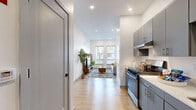 Located at 41 Seacoast Ter. in Kittery, Maine, this thoughtfully designed one-bedroom, one-bathroom unit offers a modern aesthetic with efficient use of space across a single floor. Light wood-tone flooring runs through the entry, kitchen, and living area, creating a cohesive and welcoming feel throughout.

The galley-style kitchen is outfitted with sleek gray cabinetry, a stainless steel range, refrigerator, microwave, and a clean white countertop with an undermount sink — providing a fully functional cooking space. The kitchen opens directly into the living room, which is brightened by a pair of large windows that invite natural light and offer views of the surrounding neighborhood.

The bedroom is a comfortable, well-proportioned retreat with a window, neutral walls, and a dedicated closet accessible through a private door. The bathroom features large-format tile flooring, a gray vanity with a light countertop, black matte hardware accents, a rectangular mirror, and a full soaking tub with shower. A dedicated in-unit laundry area accommodates a front-loading washer/dryer, adding everyday convenience. The overall design is clean, contemporary, and well-suited for efficient modern living.