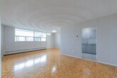 Located at 3875 Sheppard Ave E in Toronto's Scarborough district, this well-organized 2-bedroom, 1-bathroom unit offers a practical and comfortable single-floor layout. Warm parquet flooring runs throughout the living areas and bedrooms, adding a classic character to the space.

The spacious living room is a highlight, featuring a wide bank of windows that frame views of the surrounding cityscape and greenery, filling the room with abundant natural light. A textured ceiling adds visual interest, while baseboard heating lines the perimeter. The living area flows conveniently toward the kitchen, which is outfitted with grey cabinetry, granite-style countertops, a stainless steel sink, and a white electric range with ample upper and lower cabinet storage.

Both bedrooms are comfortably sized with parquet floors, neutral grey walls, and large windows overlooking the urban surroundings. The primary bedroom features a built-in double closet, while the secondary bedroom includes access to additional storage. A hallway with a closet connects the rooms efficiently.

The full bathroom is clean and functional, complete with a tiled tub-shower surround and chrome fixtures. The overall ambiance is bright and neutral, offering a move-in-ready canvas in a well-connected Toronto neighbourhood.