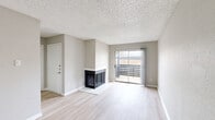 Located at 2500 Guerrero Drive in Carrollton, TX, this one-bedroom, one-bathroom unit offers a well-organized, efficiently designed layout spread across a single floor. Light wood-style flooring runs throughout the space, complementing the neutral gray tones of the walls and creating a clean, cohesive aesthetic.

The open-concept kitchen and living room area serves as the heart of the unit. The kitchen is equipped with stainless steel appliances — including a refrigerator, range, and microwave — paired with gray shaker-style cabinetry, white quartz countertops, a double undermount sink, and a classic white subway tile backsplash. The adjacent living room is highlighted by a wood-burning fireplace and a sliding glass door that opens to a private balcony, allowing for natural light and outdoor views.

The bedroom is a comfortable, well-proportioned room featuring a ceiling fan, a window with natural light, and access to a dedicated closet. The bathroom features wood-style flooring, gray cabinetry with quartz countertops, and a full tub/shower combination clad in large-format marble-style tile. A hallway connects the private areas of the unit. Textured ceilings are present throughout, adding a distinct character to the overall interior.
