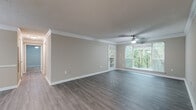 Located at 9200 Roberts Dr. in Sandy Springs, GA, this single-story residence offers a well-designed layout with a cohesive, neutral color palette throughout. The open living and dining area is highlighted by rich wood-look flooring, crown molding, and a ceiling fan with light fixture. A chandelier illuminates the dining space, which connects seamlessly to the living area through an open-concept flow. A built-in shelving unit adds functional character to the living room, while a private exterior door and large windows invite abundant natural light and views of surrounding greenery.

The galley-style kitchen is equipped with dark espresso cabinetry, light stone-look countertops, a tile backsplash, and stainless steel appliances including a range and dishwasher. A pass-through counter opening connects the kitchen to the main living area. Bedrooms feature plush carpeting, ceiling fans, and windows overlooking the wooded surroundings. The bathroom includes a full soaking tub with white tile surround, adding a clean, classic finish. Throughout the space, consistent trim work, textured ceilings, and warm tones create a comfortable and well-maintained living environment.