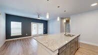 This single-story, 3-bedroom, 3-bathroom home offers a thoughtfully designed open-concept layout that maximizes comfort and functionality. The combined kitchen and living area serves as the heart of the home, featuring a large granite-topped island with an integrated sink, sleek gray shaker cabinets with gold hardware, pendant lighting, and stainless steel appliances. Light wood-look flooring runs throughout, complementing the neutral color palette accented by bold navy-blue walls in the living area. French doors bring in natural light and provide access to the outdoors, while a ceiling fan enhances airflow and comfort.

Each of the three bedrooms is well-proportioned, with large windows fitted with blinds that allow for ample natural light. The primary bedroom includes access to a dedicated closet with built-in wire shelving. Three full bathrooms are appointed with granite countertops, gray cabinetry, and tiled shower-tub combinations. Four closets throughout the home provide generous storage options, all fitted with wire rack shelving systems. A dedicated laundry room houses a full-size washer and dryer with additional wire shelving above. The home's clean, modern aesthetic and practical layout make it a highly functional living space.
