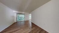Located at 2320 Timberbrook Dr SE in Grand Rapids, Michigan, this single-floor residence offers a clean, modern aesthetic highlighted by wood-look flooring that flows consistently throughout every room. The spacious living area features vaulted ceilings that enhance the sense of openness, with a sliding glass door dressed in vertical blinds that opens to a private balcony overlooking lush greenery. A secondary window alongside the slider brings in abundant natural light, creating a bright and welcoming atmosphere.

The galley-style kitchen is efficiently designed with white cabinetry, white appliances including a range, refrigerator, microwave, and dishwasher, along with ample counter space. A dedicated laundry area with a full-size washer and dryer is conveniently accessible directly from the kitchen. A breakfast bar pass-through connects the kitchen area to an adjacent dining or flex space.

The bedrooms are well-sized and naturally lit, with large windows framing outdoor tree views. One bedroom features a sliding closet with built-in storage. Two full bathrooms are present, each with a tub/shower combination and wood-look flooring. The overall palette of crisp white walls and warm flooring tones throughout creates a cohesive, move-in-ready environment ideal for comfortable everyday living.