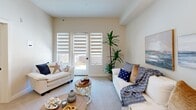 Located at 100 Glenwood Circle in Monterey, California, this single-floor, 2-bedroom, 1-bathroom unit offers a thoughtfully designed layout with a coastal aesthetic throughout. The open-concept living and dining area is bright and welcoming, featuring soft neutral walls, plush carpeting, and large windows dressed with layered roller shades that allow natural light to filter in. A sliding glass door leads to an outdoor area, further enhancing the airy feel of the space. The kitchen is well-equipped with grey shaker-style cabinetry, light quartz countertops, stainless steel appliances including a range, dishwasher, microwave, and refrigerator, and light wood-look flooring that adds warmth and contrast. The spacious primary bedroom comfortably accommodates a queen bed and additional furnishings, with a generous window and plush carpet underfoot. A hallway lined with two louvered sliding-door closets leads to the full bathroom, which features large-format tile walls and flooring, grab bars, and a clean, accessible design. A second bedroom and in-unit laundry round out this efficiently planned home, making it an ideal residence in the heart of Monterey.