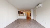 Located at 1255 Harrison St in Seattle, WA, this modern one-bedroom, one-bathroom unit offers a well-designed layout across a single floor. The open-concept living, dining, and kitchen area creates a spacious, cohesive environment anchored by light gray hardwood-style flooring throughout. Large windows flood the living area with natural light and frame views of the surrounding cityscape, enhancing the bright, airy ambiance.

The kitchen is thoughtfully appointed with stainless steel appliances — including a refrigerator, range, and microwave — complemented by two-tone cabinetry featuring light wood lower cabinets and dark upper cabinets, a white subway tile backsplash, and a peninsula with a light countertop that separates the kitchen from the living and dining space. A wall-mounted mini-split unit provides climate control in the main living area.

The bedroom offers a comfortable footprint with a sliding closet, additional storage, and windows that continue the theme of natural light. Two closets provide ample storage throughout the unit. The bathroom features a soaking tub and shower combination with white subway tile accented by a vertical dark tile inlay, a dark-cabinetry vanity with a neutral countertop, and a large mirror. The unit also benefits from a dedicated entry area adjacent to the kitchen.