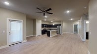 This single-story unit located along Lyndon B. Johnson Freeway in Grand Prairie, Texas, offers a well-designed, open-concept layout with contemporary finishes. The living and kitchen areas flow seamlessly together, anchored by light wood-look flooring and recessed lighting complemented by a ceiling fan overhead. The kitchen is a standout feature, outfitted with dark espresso cabinetry, speckled granite-style countertops, a central island with a built-in sink, and a full suite of stainless steel appliances including a refrigerator, range, and microwave. Ample upper and lower cabinetry provides generous storage throughout.

The bedrooms are carpeted for comfort and each includes a ceiling fan with light fixture and window with blinds, allowing natural light to enter. One bedroom features a walk-in closet with shelving, while another offers access to a well-lit secondary space. The bathrooms are finished with dark cabinetry, granite-topped vanities, and tile surround — one featuring a soaking tub and shower combination, the other a framed glass walk-in shower. Overall, the unit presents a clean, neutral palette with consistent modern detailing throughout.