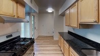 Located at 9556 Muirkirk Road in Laurel, Maryland, this single-floor unit offers a functional and well-appointed layout designed for comfortable everyday living. The galley-style kitchen is a standout feature, boasting dark granite countertops, a double sink, light maple cabinetry, and black stainless appliances including a gas range and refrigerator. Light wood-style flooring runs throughout the kitchen, which connects seamlessly to the rest of the unit. The living area is generously sized, featuring plush wall-to-wall carpeting, clean white walls, and a large window with vertical blinds that allows ample natural light to fill the space. The bedroom offers comfortable carpeted flooring and a wide double-door louvered closet, providing substantial storage. The full bathroom is neatly finished with a tub and shower combination, a light wood vanity with white countertop, and a large mirror above the sink. Wood-style flooring in the bathroom complements the overall design aesthetic. Throughout the unit, the neutral color palette and clean finishes create a bright, cohesive ambiance. The floor plan, as seen in the dollhouse view, reveals a practical and efficiently organized single-level layout ideal for easy navigation between spaces.