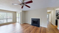 Located in the North Druid Hills neighborhood of Atlanta, Georgia, this single-floor residence offers a well-organized layout with a range of functional and comfortable living spaces. The main living area is a standout, featuring warm hardwood flooring, a ceiling fan, a textured ceiling, and a wood-burning fireplace framed in dark tile — creating an inviting focal point. Sliding glass doors open directly to a private balcony, allowing natural light to fill the space and providing outdoor views of the surrounding greenery. The galley-style kitchen is well-appointed with dark cabinetry, granite-style countertops, stainless steel appliances including a refrigerator and dishwasher, a tile backsplash, and hardwood flooring, delivering both style and practicality. The bedrooms feature plush carpeting, ceiling fans, and generous windows that bring in ample natural light. One bedroom includes direct outdoor access via a private door. The bathrooms are clean and functional, each featuring a tiled tub-shower combination. A secondary living or dining area extends the hardwood-floored space, offering flexibility in use. Throughout, neutral warm tones and consistent finishes create a cohesive and comfortable ambiance.