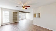 Located at 1044 Camino La Costa in Austin, TX, this single-story unit offers a well-designed layout that balances comfort and functionality. The open living area is a standout feature, showcasing warm hardwood-style flooring, crisp white walls, and a ceiling fan with a light fixture that adds both style and airflow. Built-in shelving along one wall provides convenient display and storage space, while a pass-through window connects the living area to the kitchen, enhancing the open feel of the space. Large windows allow natural light to fill the room, offering views of the surrounding greenery outside.

The kitchen is efficiently laid out with light granite-style countertops, gray cabinetry, a double stainless steel sink, and a dishwasher, providing all the essentials for everyday use. An adjacent dining or flex area features additional large windows and a decorative beam accent, further brightening the space.

The bedrooms are carpeted for comfort and include ceiling fans and mirrored sliding closet doors that maximize the sense of space. The bathroom area features hardwood-style flooring, a vanity with countertop space, and a separate water closet for added privacy. Throughout, the neutral color palette and clean finishes create a bright, welcoming ambiance.