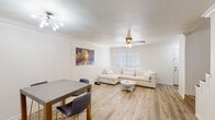 This two-story, three-bedroom, two-bathroom home in Baton Rouge, Louisiana offers a clean, modern aesthetic throughout. Light wood-look flooring flows consistently across the living spaces, creating a bright and cohesive feel. The open living and dining area is anchored by a large window that fills the room with natural light, complemented by a ceiling fan with integrated lighting and crown molding details. The kitchen is well-appointed with crisp white shaker cabinets, white countertops, black appliances including an electric range, dishwasher, and stainless steel refrigerator, plus a skylight that adds extra brightness. A dedicated laundry area houses a full-size washer and dryer beneath overhead white cabinetry for additional storage. The bedrooms are comfortably sized with the same light flooring and ceiling fans. The bathrooms feature white vanity cabinetry, framed mirrors, and bright vanity lighting. The overall design is neutral and light-toned throughout, with white walls and trim creating a clean, move-in-ready atmosphere. The two-floor layout, as revealed in the dollhouse view, provides a practical and well-organized flow between living and private spaces.