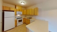 Located at 4400 E Lake Rd in Erie, Pennsylvania, this single-floor residence offers a well-organized and functional layout designed for comfortable everyday living. The heart of the home is an open-concept kitchen and living area, where warm honey-toned cabinetry lines the kitchen walls, providing generous storage space. The kitchen is equipped with a full suite of appliances, including a refrigerator, electric range, built-in microwave, and dishwasher. Light countertops and tile flooring complete the kitchen's clean, practical aesthetic, while a peninsula counter creates a natural divide between the kitchen and the adjoining living space. A chandelier pendant light adds a touch of elegance above the peninsula. The living area features neutral-toned carpet and a door with a window that invites natural light and outdoor views. The bedrooms are carpeted and well-proportioned, each featuring windows with blinds that frame views of the surrounding greenery, filling the rooms with soft, natural light. The bathroom is finished with tile flooring, a vanity with sink, a toilet, and a glass-door shower. Accessibility-conscious grab bars are thoughtfully installed, reflecting a commitment to inclusive design. Neutral wall tones and consistent finishes throughout the space create a cohesive, understated ambiance.