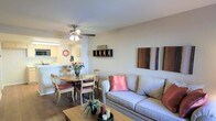 This single-floor space offers a warm and inviting layout centered around an open-concept living and dining area. The living room features rich hardwood flooring, neutral walls, and a ceiling fan with integrated lighting that provides both comfort and illumination. Wall-mounted décor accents add a personalized touch to the space, complementing the relaxed aesthetic throughout.

Adjacent to the living area, the dining space accommodates a round wooden table with cushioned chairs, creating an intimate setting for meals. A pass-through counter connects the dining area directly to the kitchen, which is equipped with overhead cabinetry, under-cabinet lighting, and built-in appliances. This open connection between the kitchen and the living-dining area promotes a seamless flow and makes the space feel bright and interconnected.

The overall design is practical and functional, with a layout that maximizes the use of available space. The consistent hardwood flooring throughout the main living areas ties the rooms together visually and adds warmth to the interior. The ceiling fan serves as both a design feature and a practical element, ensuring air circulation across the open floor plan. Together, these features create a cohesive and comfortable single-floor living environment.