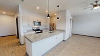 Located at 1525 N Main Street in Marion, Indiana, this thoughtfully designed single-floor residence offers a clean, modern aesthetic with quality finishes throughout. The kitchen serves as the heart of the home, showcasing a large granite-topped island with an undermount sink, sleek white cabinetry, and a full suite of stainless steel appliances including a range, microwave, and refrigerator. Light wood-tone luxury vinyl plank flooring runs through the kitchen and main living areas, complemented by stylish pendant lighting that adds a contemporary touch. The open layout allows for a natural flow between the kitchen and living spaces. The bedrooms are generously sized and feature plush wall-to-wall carpeting, ceiling fans, and windows that invite natural light into the rooms. One bedroom provides convenient access to in-unit laundry facilities, adding to the overall practicality of the space. The bathrooms are well-appointed, with one featuring a granite-topped vanity with modern cabinetry and wood-look flooring, while both include a full tub-shower combination. Throughout the residence, crisp white walls, clean lines, and consistent finishes contribute to a bright and welcoming atmosphere that feels both functional and contemporary.