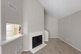 Located in Houston, TX, this two-story, 2-bedroom, 3-bathroom home offers a well-organized layout spread across two floors. The main level is the larger of the two, anchored by a bright, open living area with dramatic vaulted ceilings that lend an airy, expansive feel. A standout marble-surround fireplace serves as the focal point of the living room, complemented by soft carpeting and neutral gray tones throughout. A pass-through counter connects the living area to the galley-style kitchen, which features white cabinetry, white appliances, a marble-look countertop, a skylight, and light wood-look flooring—creating a clean, functional workspace. The combined dining and kitchen area flows seamlessly for everyday living. A dedicated laundry area adds convenience. Upstairs, the primary bedroom is generously sized with a ceiling fan, natural light from a window with blinds, and comfortable carpeting. Multiple closets throughout the home, including well-shelved walk-in storage spaces, provide ample organization. Three full bathrooms, including one with a tub-shower combination, serve the household efficiently. The home's consistent neutral palette, vaulted ceilings, and practical two-floor layout make it a functional and comfortable residence.