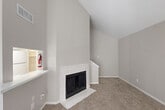 Located in Houston, TX, this two-story, 2-bedroom, 3-bathroom home offers a well-organized layout spread across two floors. The main level is the larger of the two, anchored by a bright, open living area with dramatic vaulted ceilings that lend an airy, expansive feel. A standout marble-surround fireplace serves as the focal point of the living room, complemented by soft carpeting and neutral gray tones throughout. A pass-through counter connects the living area to the galley-style kitchen, which features white cabinetry, white appliances, a marble-look countertop, a skylight, and light wood-look flooring—creating a clean, functional workspace. The combined dining and kitchen area flows seamlessly for everyday living. A dedicated laundry area adds convenience. Upstairs, the primary bedroom is generously sized with a ceiling fan, natural light from a window with blinds, and comfortable carpeting. Multiple closets throughout the home, including well-shelved walk-in storage spaces, provide ample organization. Three full bathrooms, including one with a tub-shower combination, serve the household efficiently. The home's consistent neutral palette, vaulted ceilings, and practical two-floor layout make it a functional and comfortable residence.