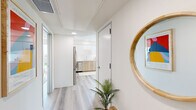 Located at 3170 W Olympic Blvd in Los Angeles, this modern single-floor unit presents a clean, contemporary aesthetic defined by light-toned wood flooring, crisp white walls, and an abundance of natural light throughout. The layout flows naturally from a welcoming hallway — accented by a round wood-framed mirror and decorative greenery — into the various living spaces beyond.

The kitchen is a standout feature, showcasing a thoughtfully designed two-tone scheme with white upper cabinetry and warm natural wood lower cabinets, complemented by white quartz countertops and a rectangular tile backsplash. Stainless steel appliances, including a refrigerator, range, microwave, and dishwasher, complete the functional and stylish cooking space.

Multiple bedrooms offer comfortable retreats, each featuring light wood flooring, warm neutral wall tones, and large windows that frame views of the Los Angeles cityscape. One bedroom includes a dedicated walk-in closet, adding to the unit's practical appeal.

The bathrooms maintain the space's modern sensibility, with large-format gray tile surrounds in the tub-shower combinations, wood-toned vanity cabinetry, and light wood-effect flooring that ties the design together cohesively.

Throughout the unit, recessed lighting and a neutral, airy palette create a calm and inviting atmosphere well-suited to urban living in the heart of Los Angeles.