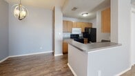 Located at 1301 N State Highway 121 in Bonham, Texas, this 2-bedroom, 1-bathroom unit offers a practical and comfortable single-floor layout. The kitchen is well-equipped with warm wood-toned cabinetry, granite-style countertops, black appliances including a range, refrigerator, and built-in microwave, and durable wood-look flooring. A breakfast bar provides additional counter space and separates the kitchen from the adjacent living area, which features the same hard-surface flooring for easy maintenance. Both bedrooms are carpeted and painted in soft, neutral tones, each featuring ceiling fans with light fixtures for comfort and airflow. The spacious primary bedroom includes a closet and offers a relaxed, functional retreat. The second bedroom is also well-proportioned with a window that brings in natural light. The bathroom is thoughtfully designed with wood-toned cabinetry, a granite-style vanity countertop, a large mirror, and wood-look flooring, providing a clean and cohesive aesthetic. Throughout the unit, textured ceilings and clean white trim add a consistent, tidy finish. A dedicated closet adds to the storage options available within this efficiently designed home.