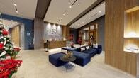 Located on Coral Way in Miami, FL, MB Station's lobby and leasing center presents a polished, contemporary design across a single floor. The space is anchored by a striking reception desk combining marble-finish surfaces and warm wood slat detailing, set against a marble-clad accent wall bearing the MB Station logo. Recessed ceiling lighting illuminates the open layout, while varied ceiling heights add architectural dimension throughout.

The main lobby area features large-format stone-look tile flooring and a generously sized navy blue modular sectional sofa, creating an inviting lounge environment. Warm wood-clad columns with built-in illuminated display niches serve as focal design elements, adding texture and depth. A living moss wall with a modern pendant chandelier introduces a natural element near the floor-to-ceiling glazed facade, which provides direct views of the landscaped streetscape outside.

Colorful framed artwork and a wall-mounted display screen enhance the gallery-like atmosphere. A glazed-partition private office area, accessible through gold-framed glass doors, offers a functional workspace for leasing staff. The entry vestibule features double doors with branded matting, providing a defined and professional arrival experience. Overall, the space balances sophistication with approachability.