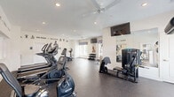 Located at 1900 Breccan Meadows Dr in Columbus, OH, this fitness center offers a thoughtfully designed exercise space with everything needed for a comprehensive workout. The room features durable rubber-speckled flooring throughout, providing a safe and resilient surface for all types of exercise activity.

Natural light fills the space through multiple windows dressed with decorative patterned valances and white horizontal blinds, creating a bright and energizing atmosphere. Ceiling fans ensure comfortable air circulation during intense workouts, while recessed lighting adds consistent illumination throughout.

The exercise room is well-stocked with a diverse range of equipment. Cardio options include treadmills and an elliptical machine, while a stationary bike offers additional low-impact training. For strength training, the space provides a multi-functional cable and weight machine, an adjustable workout bench, and a tiered dumbbell rack with a full range of free weights. A medicine ball and resistance band station round out the functional fitness offerings.

Wall-mounted flat-screen televisions are positioned at multiple angles for entertainment during workouts. Large mirrors along one wall enhance the sense of space and allow for form checks. Motivational phrases such as "Focus. Fight. Finish. Repeat." are displayed prominently on the walls, reinforcing an energetic and goal-oriented environment. The overall ambiance is clean, modern, and purpose-built for fitness.