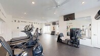 Located at 1900 Breccan Meadows Dr in Columbus, OH, this fitness center offers a thoughtfully designed exercise space with everything needed for a comprehensive workout. The room features durable rubber-speckled flooring throughout, providing a safe and resilient surface for all types of exercise activity.

Natural light fills the space through multiple windows dressed with decorative patterned valances and white horizontal blinds, creating a bright and energizing atmosphere. Ceiling fans ensure comfortable air circulation during intense workouts, while recessed lighting adds consistent illumination throughout.

The exercise room is well-stocked with a diverse range of equipment. Cardio options include treadmills and an elliptical machine, while a stationary bike offers additional low-impact training. For strength training, the space provides a multi-functional cable and weight machine, an adjustable workout bench, and a tiered dumbbell rack with a full range of free weights. A medicine ball and resistance band station round out the functional fitness offerings.

Wall-mounted flat-screen televisions are positioned at multiple angles for entertainment during workouts. Large mirrors along one wall enhance the sense of space and allow for form checks. Motivational phrases such as "Focus. Fight. Finish. Repeat." are displayed prominently on the walls, reinforcing an energetic and goal-oriented environment. The overall ambiance is clean, modern, and purpose-built for fitness.