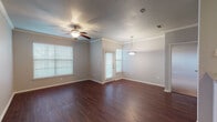 This single-floor residence offers a thoughtfully designed layout with a cohesive blend of style and functionality. The open living and dining area sets the tone with rich, dark hardwood flooring, crown molding, and a ceiling fan overhead. Large windows dressed with horizontal blinds fill the space with natural light, while a pendant light anchors the dining area. A door provides direct exterior access from this main living space.

The kitchen is equipped with dark espresso cabinetry, granite countertops, and a full suite of stainless steel appliances, including a range, over-the-range microwave, and dishwasher. A peninsula with a granite overhang connects the kitchen to the main living area, creating an open, accessible flow.

The bedrooms feature plush carpeting, ceiling fans with light fixtures, and windows that bring in ample natural light, giving each room a comfortable and relaxed atmosphere.

The bathroom is finished with dark wood cabinetry, a granite vanity top, white tile surround for the tub-shower combination, and hardwood flooring, maintaining the consistent design language found throughout the home.

Overall, the space presents a clean, neutral palette with warm wood tones and stone accents, offering a practical and inviting environment.