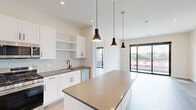 This modern 2-bedroom, 2-bathroom residence at 630 Washington Avenue in Belleville, NJ offers a thoughtfully designed open-concept layout with contemporary finishes throughout. The combined kitchen and living area serves as the heart of the home, featuring wide-plank hardwood-style flooring, recessed lighting, and floor-to-ceiling sliding glass doors that open to a private balcony with glass railings and expansive views of the surrounding neighborhood. The kitchen is outfitted with crisp white shaker cabinetry accented by matte black hardware, gray quartz countertops, a decorative mosaic tile backsplash, stainless steel appliances, and a center island with pendant lighting above. Both bedrooms are bright and airy, bathed in natural light, with clean neutral walls and hardwood-style flooring. The primary bedroom features access to an outdoor balcony through large sliding glass doors, while additional closets provide ample storage throughout. The two bathrooms showcase modern design with gray quartz vanities and matte black fixtures. One bathroom offers an accessible layout with grab bars and a glass-enclosed shower, while the second features large-format gray tile surrounding a soaking tub-shower combination. The overall aesthetic is clean, contemporary, and move-in ready.