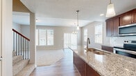 Located at 3670 NE Akin Dr in Lee's Summit, MO, this two-story home offers a well-designed layout spread across two floors. The main level features an open-concept kitchen and living area with warm hardwood-style flooring. The kitchen is a standout, showcasing rich dark cabinetry, granite countertops, stainless steel appliances, and a central island with a built-in sink and pendant lighting overhead — ideal for both cooking and entertaining. The living area flows seamlessly from the kitchen, bathed in natural light from multiple large windows that provide views of the surrounding neighborhood. A chandelier adds a refined touch to the dining space nearby. Upstairs, three carpeted bedrooms offer comfortable retreats, each featuring neutral tones, natural light from windows with blinds, and ample closet space. The generously sized primary bedroom provides a quiet sanctuary. The home includes three full bathrooms; the primary bath features a double-sink vanity with rich wood cabinetry, a large mirror, tile flooring, and a walk-in tiled shower. Additional bathrooms include a tub-shower combination. A staircase with wood and wrought-iron detailing connects both levels, and a hallway provides easy access throughout the upper floor.