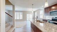 Located at 3670 NE Akin Dr in Lee's Summit, MO, this two-story home offers a well-designed layout spread across two floors. The main level features an open-concept kitchen and living area with warm hardwood-style flooring. The kitchen is a standout, showcasing rich dark cabinetry, granite countertops, stainless steel appliances, and a central island with a built-in sink and pendant lighting overhead — ideal for both cooking and entertaining. The living area flows seamlessly from the kitchen, bathed in natural light from multiple large windows that provide views of the surrounding neighborhood. A chandelier adds a refined touch to the dining space nearby. Upstairs, three carpeted bedrooms offer comfortable retreats, each featuring neutral tones, natural light from windows with blinds, and ample closet space. The generously sized primary bedroom provides a quiet sanctuary. The home includes three full bathrooms; the primary bath features a double-sink vanity with rich wood cabinetry, a large mirror, tile flooring, and a walk-in tiled shower. Additional bathrooms include a tub-shower combination. A staircase with wood and wrought-iron detailing connects both levels, and a hallway provides easy access throughout the upper floor.