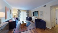 This single-floor residence offers a thoughtfully designed layout that balances comfort and functionality across its key living spaces. The living room serves as the heart of the home, featuring warm hardwood flooring, crown molding, and a large sliding glass door that floods the space with natural light and provides access to an outdoor area. The room offers generous space for entertaining and relaxing.

The galley-style kitchen is efficiently laid out with warm wood cabinetry, granite-toned countertops, tile flooring, and a full suite of appliances including an electric range, refrigerator, and dishwasher. A dedicated pantry provides additional storage convenience.

The primary bedroom is spacious and carpeted, with a ceiling fan, multiple windows with natural light, and ample room for a large bed and additional furnishings. The second bedroom is equally comfortable, also carpeted with ceiling fan, a natural light window, and notably features two separate closets, offering excellent storage capacity.

Both bathrooms share a clean, classic design with white vanities, over-toilet cabinetry for added storage, tiled flooring, and tub-shower combinations. The overall ambiance throughout the residence is warm and inviting, with neutral wall tones providing a versatile backdrop across all rooms.
