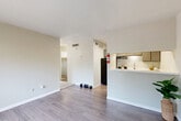 Located at 2305 Hayes Rd in Houston, TX, this single-floor unit offers a practical and well-organized layout. The open-concept living and dining area serves as the heart of the space, featuring wood-look vinyl flooring that runs throughout, neutral warm-gray walls, and a large window fitted with horizontal blinds that allows natural light to filter in and brighten the room.

The kitchen is positioned adjacent to the living area and is defined by a white peninsula counter that doubles as a pass-through, providing both additional workspace and a natural separation between rooms. It is equipped with a black refrigerator, a gas range, an under-cabinet range hood, and taupe cabinetry offering ample storage. A single-basin sink with a window above completes the functional setup.

The bedroom is a quiet, neutral space with the same wood-look flooring, clean white walls, and a built-in closet with sliding doors for convenient storage. The bathroom features a vanity with a white countertop and an integrated sink, framed mirror with overhead lighting, and direct access to an open closet area, keeping the layout efficient.

Throughout the unit, white trim and baseboards provide clean contrast against the neutral palette, creating a cohesive and tidy aesthetic suitable for comfortable everyday living.