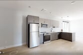 Unit 501 at 1213–1221 Broad St is a thoughtfully designed two-bedroom residence situated on the fifth floor, offering an efficient and modern living layout across a single level. Light-toned hardwood flooring runs throughout the unit, lending warmth and continuity to the space.

The kitchen is a standout feature, equipped with two-tone flat-panel cabinetry in a warm gray wood finish, white quartz countertops, and a classic white subway tile backsplash. Stainless steel appliances — including a GE range, over-the-range microwave, dishwasher, and refrigerator — complete the contemporary setup. A matte black faucet at the undermount sink adds a modern accent. Pendant lighting above the counter enhances both form and function.

The two bedrooms are bright and airy, each featuring large windows that frame open city views of the surrounding neighborhood and skyline. Natural light fills both rooms throughout the day. Each bedroom includes a wall-mounted HVAC unit for individual climate control.

The open floor plan connects the kitchen and living areas seamlessly, making the overall layout feel spacious and functional. Clean white walls, modern finishes, and abundant natural light create a fresh, contemporary ambiance throughout the unit, well-suited for urban living.