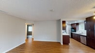 Located at 2460 Bear Valley in Escondido, this single-story unit offers a well-organized layout connecting the living, dining, and kitchen areas in an open, cohesive flow. Wood-style flooring runs throughout the main living spaces and bedrooms, providing a consistent and warm aesthetic. The textured ceilings and neutral gray walls create a clean, understated backdrop throughout.

The kitchen is a standout feature, equipped with rich dark-wood cabinetry extending to the ceiling, light quartz-style countertops, recessed lighting, and stainless steel appliances including a gas range, built-in microwave, dishwasher, and refrigerator. A peninsula provides additional prep space and a natural division between the kitchen and living area. A stacked washer and dryer unit is conveniently housed within the kitchen area.

The living and dining spaces are open and well-lit, with natural light provided by windows fitted with vertical blinds. A ceiling fan with lighting serves the dining area. The bedrooms each feature wood-style flooring, closets with paneled doors, and windows that allow natural light. The bathroom includes a shower/tub combination, a dark-wood vanity with a white sink, and a large mirror.

A hallway connects the private areas of the unit, maintaining a clear and functional layout throughout.