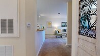 Located at Floral Springs Blvd in Port Orange, Florida, this single-story residence offers a well-designed, open-concept layout that balances functionality with a warm, inviting ambiance. Neutral tones, plush carpeting throughout the living areas, and tile flooring in the kitchen and bathrooms create a cohesive interior palette.

The kitchen is thoughtfully laid out in a galley style, featuring warm wood cabinetry, black appliances including a range and refrigerator, a built-in dishwasher, and light tile flooring. A breakfast bar connects the kitchen to the adjacent dining area, which is defined by a teal accent wall and receives overhead lighting, creating a distinct yet open dining space.

The living room is bright and comfortable, with natural light filtering through large windows dressed with decorative curtains. The bedrooms are carpeted and well-proportioned, each offering natural light through windows and ample space for furnishings. One bedroom includes a ceiling fan, while another features softer, warmer lighting suited for a primary suite.

The bathroom presents a clean, functional design with a wide vanity, a large mirror, tile flooring, and a shower enclosure. Throughout the residence, the consistent use of warm neutral walls and soft lighting contributes to a relaxed, comfortable atmosphere.
