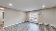 Located at 18 Brookside Ave in Worcester, MA, this single-floor unit has been thoughtfully updated with a cohesive, modern aesthetic throughout. The living area features light gray luxury vinyl plank flooring, recessed lighting, and a wall-mounted air conditioning unit. French doors allow natural light to fill the space and provide views of the surrounding neighborhood, while a baseboard heating system ensures year-round comfort.

The kitchen is well-appointed with white shaker-style cabinetry, white quartz countertops, a stainless steel sink with a brushed nickel faucet, and a gray subway tile backsplash that extends across the walls. Stainless steel appliances, including a dishwasher and refrigerator, complete the space. An adjacent entry area offers a closet and direct exterior access.

The bedrooms are carpeted in soft gray, each featuring baseboard heating and windows with blinds that provide natural light. The primary bedroom includes a closet with bi-fold doors. The bathroom is finished with gray subway tile surrounding the tub and shower, light wood-look flooring, a white vanity with brushed nickel hardware, and a framed mirror, presenting a clean and cohesive design.