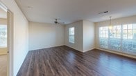 Located at 5328 W Market St in Greensboro, NC, this single-floor unit offers a well-organized layout with a comfortable blend of practical finishes and functional design. The main living area is spacious and open, showcasing rich, dark hardwood-style flooring and multiple windows that invite generous natural light, creating a bright and airy atmosphere. A ceiling fan overhead adds year-round comfort to the space.

The kitchen features a convenient pass-through counter that connects it to the main living area, promoting an open feel. Light maple cabinetry lines the walls, offering ample storage, and is complemented by light-toned countertops. White appliances, including a range and over-the-range microwave, complete the kitchen's functional setup.

A separate bedroom is finished with plush wall-to-wall carpeting and its own window overlooking greenery outside, providing a quiet and restful retreat. The ceiling fan in this room adds to the comfortable environment.

The bathroom is clean and straightforward, featuring a full tub-shower combination with a curved curtain rod, dark hardwood-style flooring consistent with the rest of the unit, and classic white fixtures. Textured ceilings are present throughout, adding a subtle architectural detail to the overall interior.