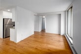 Located on the third floor at 111 Market St in the heart of Hamilton, Ontario, this 2-bedroom, 1-bathroom unit offers a well-organized layout across a single level. The living room is a bright and open space featuring warm hardwood flooring, large sliding glass doors that open to a balcony, and an additional window that frames views of the downtown Hamilton skyline. Baseboard heating runs along the perimeter, providing efficient warmth throughout.

The kitchen is outfitted with white cabinetry, a subway tile backsplash, light countertops, and stainless steel appliances including an electric range and an over-the-range microwave, creating a clean and functional cooking space.

Both bedrooms feature the same warm hardwood flooring found throughout the unit, large windows with urban views, and baseboard heaters. The primary bedroom includes a sliding-door closet, offering convenient built-in storage. The second bedroom is a comfortable and well-lit space.

The bathroom is finished with white large-format wall tiles and includes a full bathtub with an overhead shower and chrome fixtures, maintaining a clean, minimal aesthetic. A hallway connects the rooms efficiently, and a dedicated entrance provides a proper transition into the home.