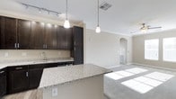 The Haven 2-bedroom, 2-bathroom residence is a well-appointed single-floor home designed for comfortable, modern living. The open-concept layout connects the kitchen and living area seamlessly, creating a spacious and inviting atmosphere filled with natural light.

The kitchen is a standout feature, showcasing rich dark espresso cabinetry that extends to the ceiling, providing generous storage space. Granite countertops with subtle veining add an elegant touch, while a large kitchen island with a breakfast bar serves as both a functional workspace and a casual dining spot. Pendant lighting suspended from the ceiling illuminates the island, complementing the track lighting above the main kitchen area. Stainless steel appliances and a deep undermount sink complete the space.

The living area flows naturally from the kitchen, featuring plush carpeting, a ceiling fan, and a decorative arched entryway that adds architectural character. Crown molding runs throughout the main living spaces, lending a refined, polished aesthetic to the home.

The neutral, warm color palette on the walls pairs harmoniously with the dark cabinetry and light granite surfaces, creating a balanced and welcoming ambiance throughout. The overall design reflects a combination of practicality and style, making this residence a comfortable and attractive place to call home.