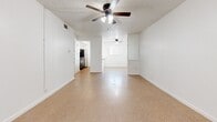 Located in Austin's 78757 zip code, this two-bedroom, one-bathroom home offers a practical and functional single-floor layout. The open living area greets you at the entrance, featuring neutral vinyl tile flooring, a textured ceiling, and a ceiling fan with light fixture. The space flows directly into the kitchen, which is outfitted with white cabinetry, a peninsula countertop with an integrated sink, stainless steel appliances including a refrigerator and range, and a stylish track light fixture overhead — making it an efficient and well-equipped cooking space.

Both bedrooms share a consistent design aesthetic with the same vinyl tile flooring, white walls, and ceiling fans. The primary bedroom is notably spacious and includes a large double-door closet alongside an additional single closet, providing ample storage. The secondary bedroom is bright and comfortable, benefiting from a window with views of surrounding greenery.

The full bathroom features white subway tile surrounding a full-length soaking tub and shower combination, a white tile floor, a toilet, and a dark wood vanity with countertop storage. A hallway connects the rooms, completing the efficient and cohesive layout of this well-maintained Austin home.