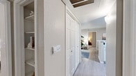 This single-floor, 3-bedroom, 2-bathroom residence offers a thoughtfully designed layout that maximizes every square foot of its compact footprint. The living room serves as the heart of the home, featuring light hardwood-style flooring, neutral walls, and large windows with a glass door that floods the space with natural light and provides outdoor access. Adjacent to the living room, the dining area offers a defined space with light flooring and a wall-mounted shelf, creating an intimate setting for gatherings. The galley-style kitchen is efficiently designed with white cabinetry, stainless steel appliances, and ample counter space. The primary bedroom features plush carpeting, a ceiling fan, and a closet, while the additional bedrooms are similarly appointed with ceiling fans and natural light. Both bathrooms are clean and functional, featuring white vanity cabinetry, light hardwood-style flooring, and one includes a full tub-shower combo with white tile surround. A central hallway connects the bedrooms and includes a built-in closet for added storage. Throughout the residence, a cohesive neutral color palette and light flooring create a bright, welcoming ambiance.