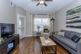 This single-floor residence offers a thoughtfully designed layout that balances comfort and functionality across a range of well-appointed spaces. The open-concept kitchen is a standout feature, showcasing rich dark-wood cabinetry, granite countertops, stainless steel appliances, pendant lighting, and a generously sized island with bar seating—all set atop warm hardwood-style flooring that extends throughout the main living areas. A hallway connects the kitchen to the rest of the unit, maintaining a clean and organized flow. The living room is bright and welcoming, with large windows that invite natural light and views of the outdoors, complemented by stylish hardwood-style flooring and neutral wall tones. The primary bedroom is a refined retreat, featuring a tray ceiling with a ceiling fan, a bold accent wall in deep charcoal, plush carpeting, and a window with outdoor views. Its en-suite bathroom includes a dual-sink granite vanity with dark wood cabinetry. A second bathroom mirrors the same quality finishes with a single-sink granite vanity. A versatile home office or flex room features carpet, multiple windows with natural light, and ample space for a drafting table or desk setup. The in-unit laundry closet houses a full-size washer and dryer. Throughout, neutral tones and consistent finishes create a cohesive and polished aesthetic.