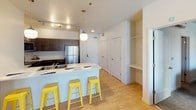 Located at 333 Nord Ave in Chico, California, this single-floor unit offers a thoughtfully designed layout with modern finishes throughout. The kitchen serves as a central feature, outfitted with dark espresso cabinetry, stainless steel appliances including a refrigerator, range, and built-in microwave, plus a white-countertop peninsula with seating for multiple occupants. Two globe pendant lights and a track lighting system illuminate the space effectively. Light wood-style flooring runs throughout the main living areas, lending a clean, cohesive aesthetic.

The living area is bright and functional, with large windows that invite natural light and provide views of the surrounding exterior. The bedrooms are carpeted and include ceiling fans with integrated lighting, windows for natural light, and dedicated study areas with desks and ergonomic chairs, making them well-suited for academic use.

The bathrooms feature dark vanity cabinetry paired with granite-style countertops. One bathroom includes a double-sink vanity, while another offers a single-sink configuration, both with a separated water closet. Built-in shelving and ample closet space near the entry add practical storage solutions to this well-appointed unit.
